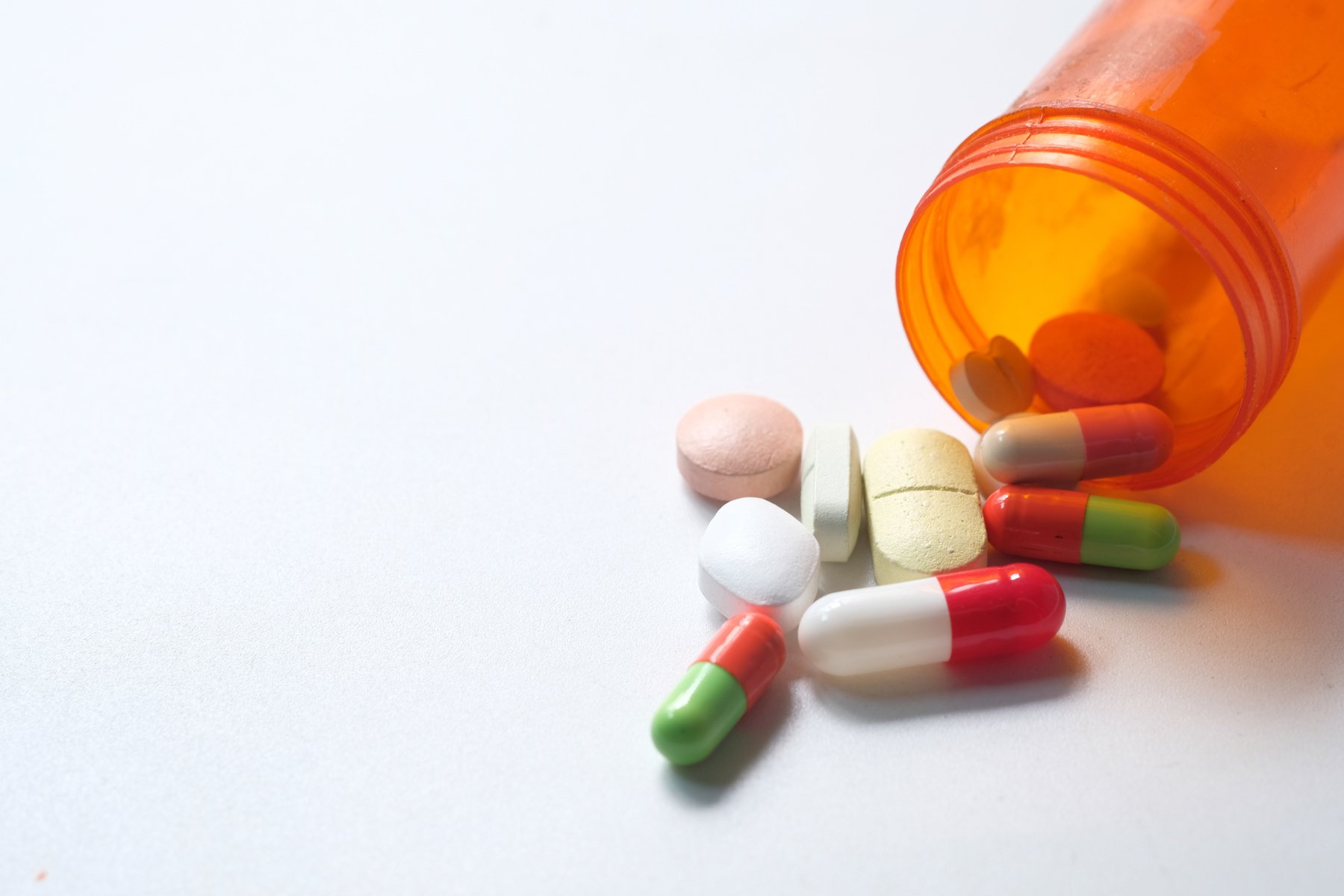 Close up of Colorful Pills Spilling on White Background